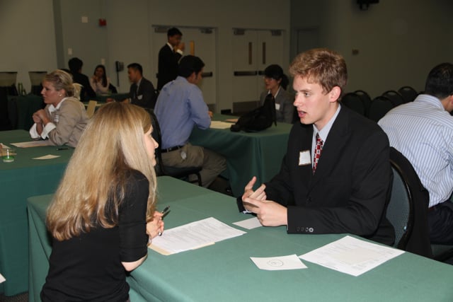 A recruiter interviewing a job candidate across a desk, illustrating the two-sided client and candidate relationship staffing firms manage in their ATS and CRM.